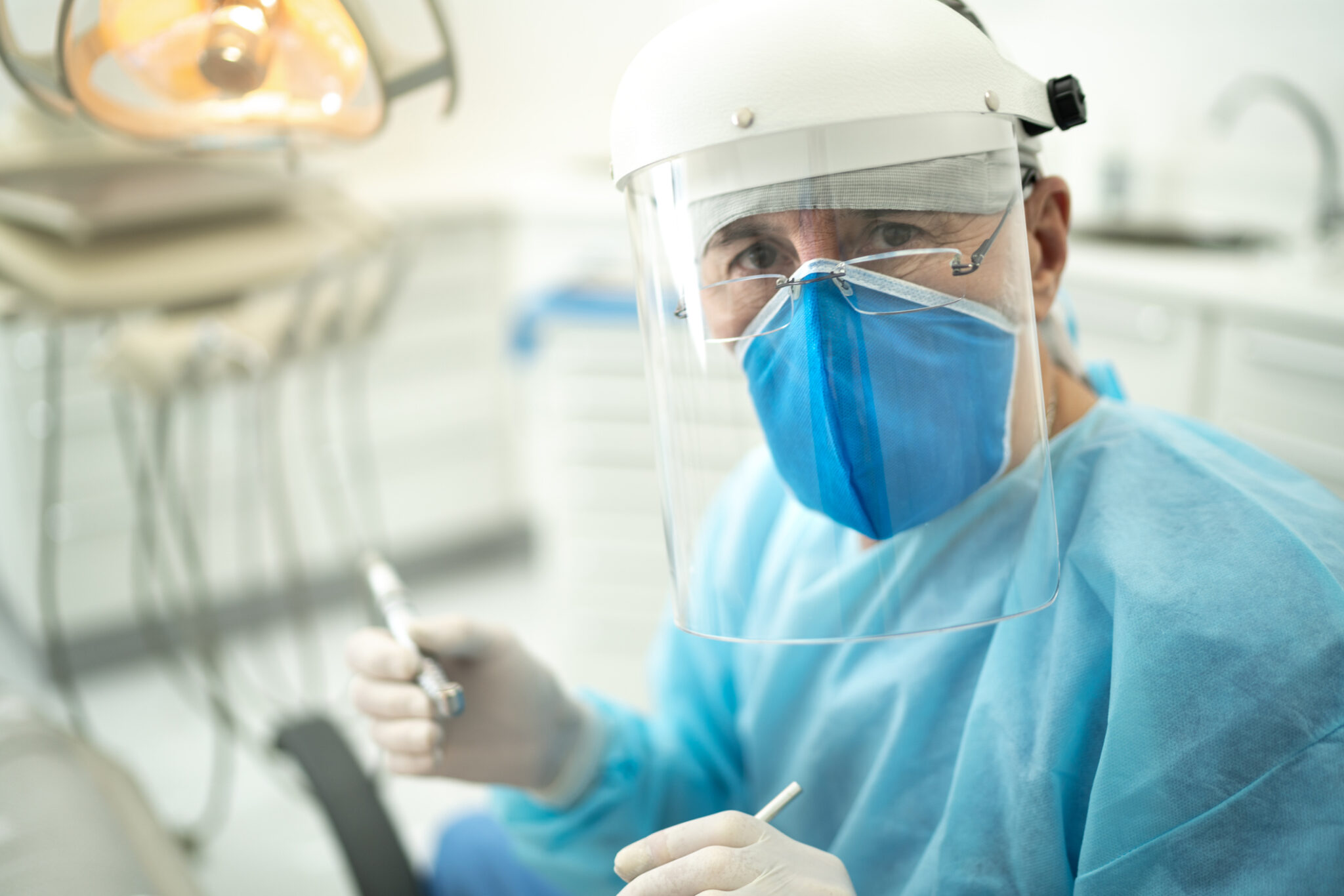 Portrait of a senior dentist examining the teeth of a young woman alternate text for this image