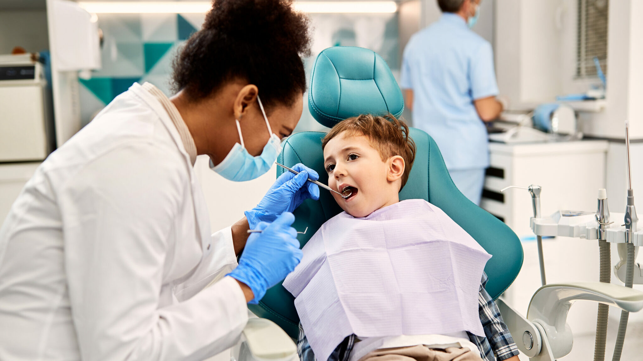 Little boy getting his teeth checked by dentist at dental clinic. alternate text for this image