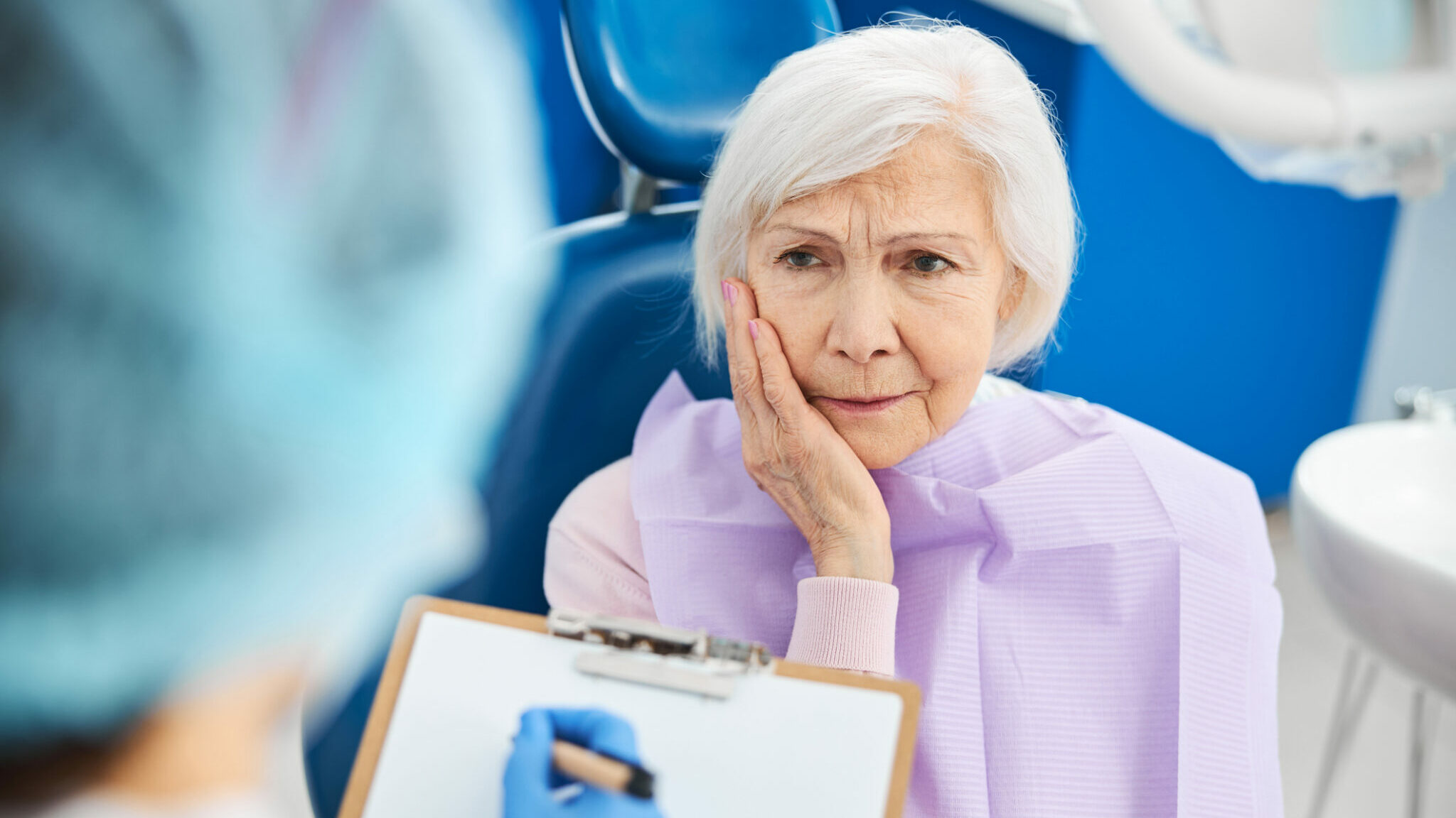 Retired woman feeling tooth pain and informing dentist alternate text for this image