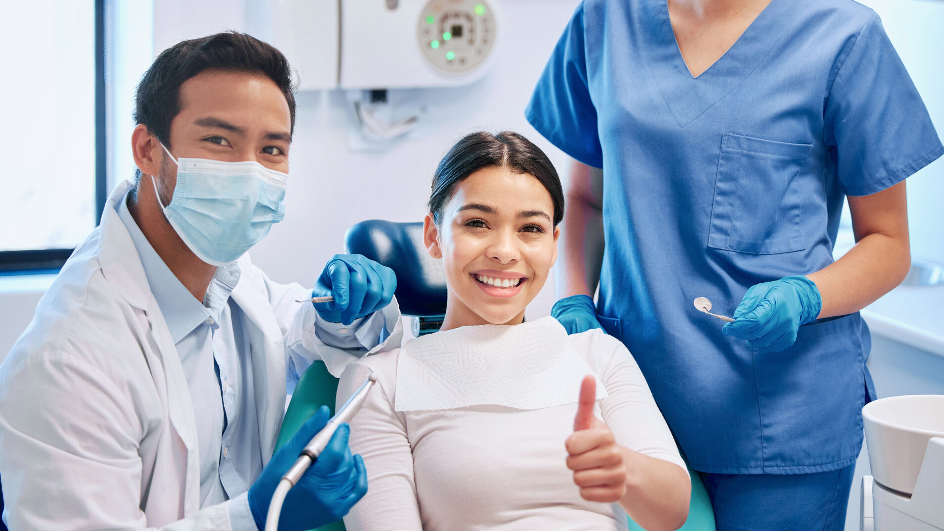 Shot of a young male dentist giving the thumbs up with his patient and assistant alternate text for this image