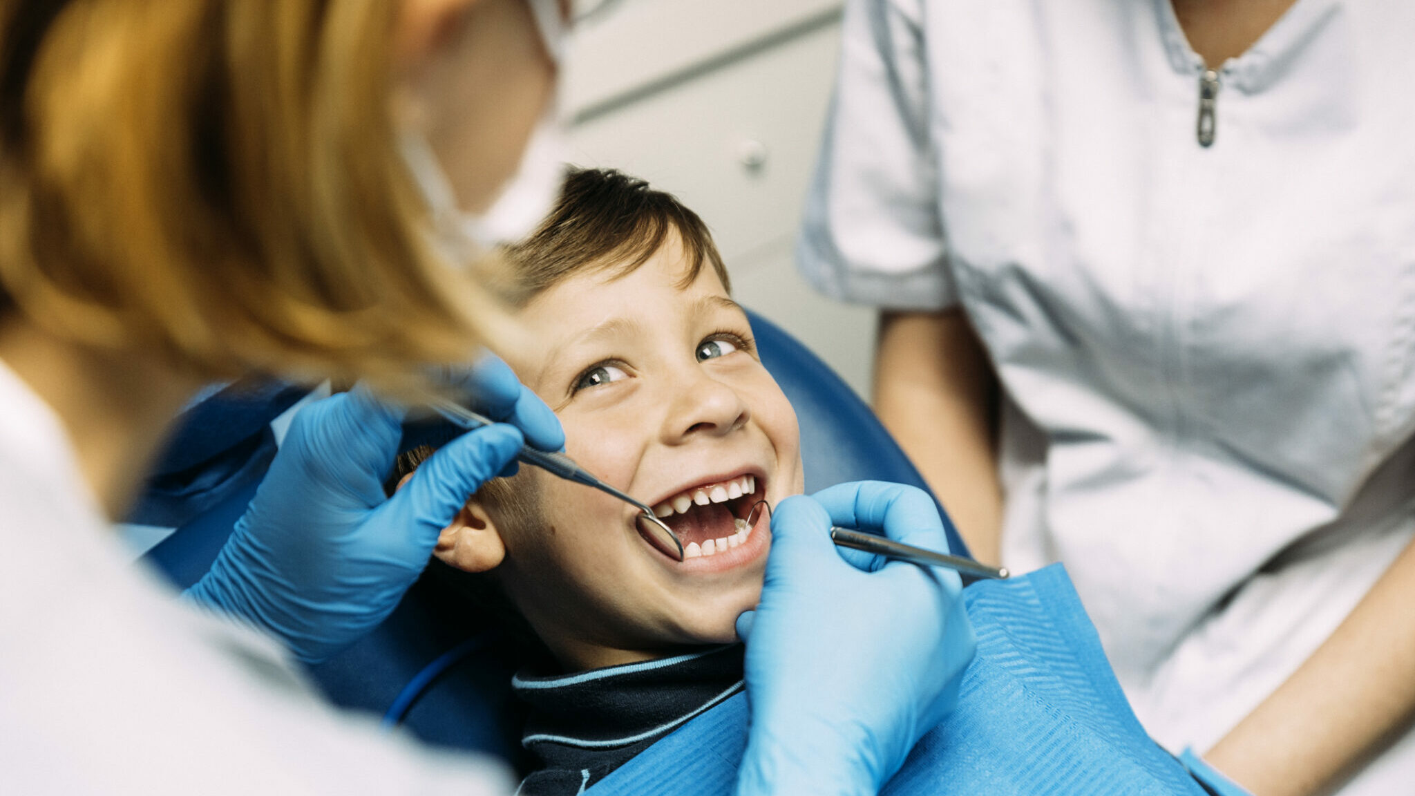 Dentists with a patient during a dental intervention to boy. alternate text for this image
