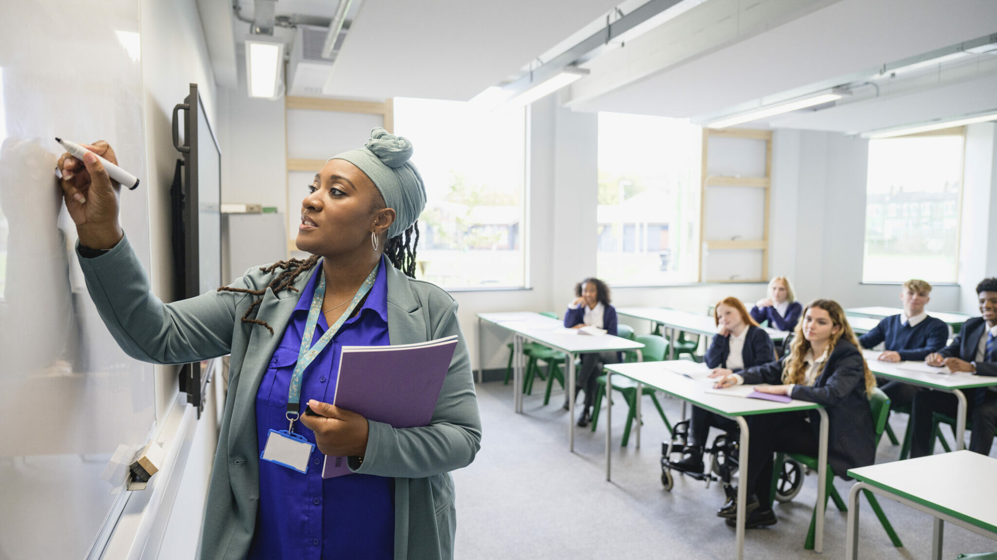 Mature Black instructor writing on whiteboard alternate text for this image