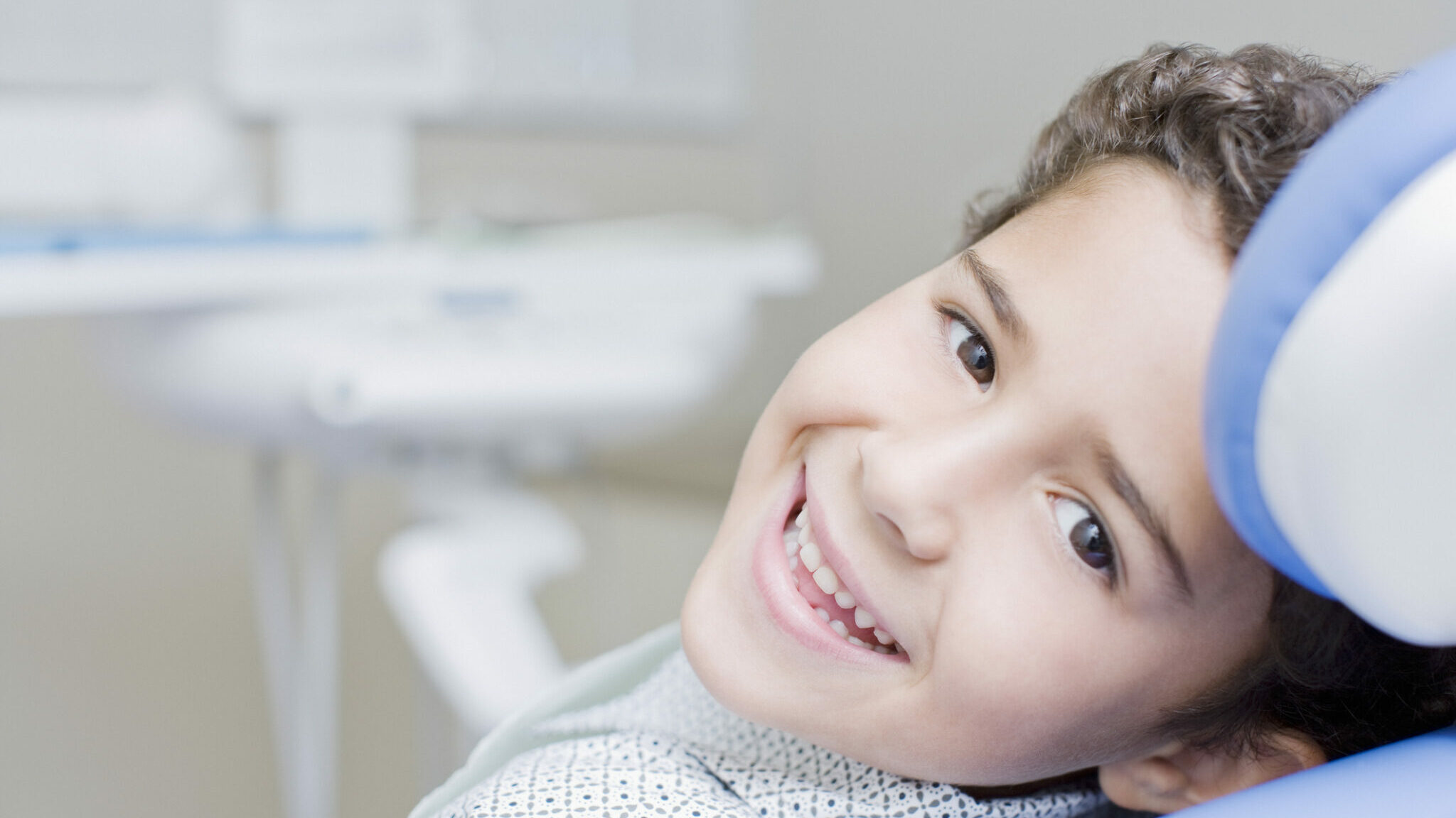 Boy smiling and sitting in dentists chair alternate text for this image