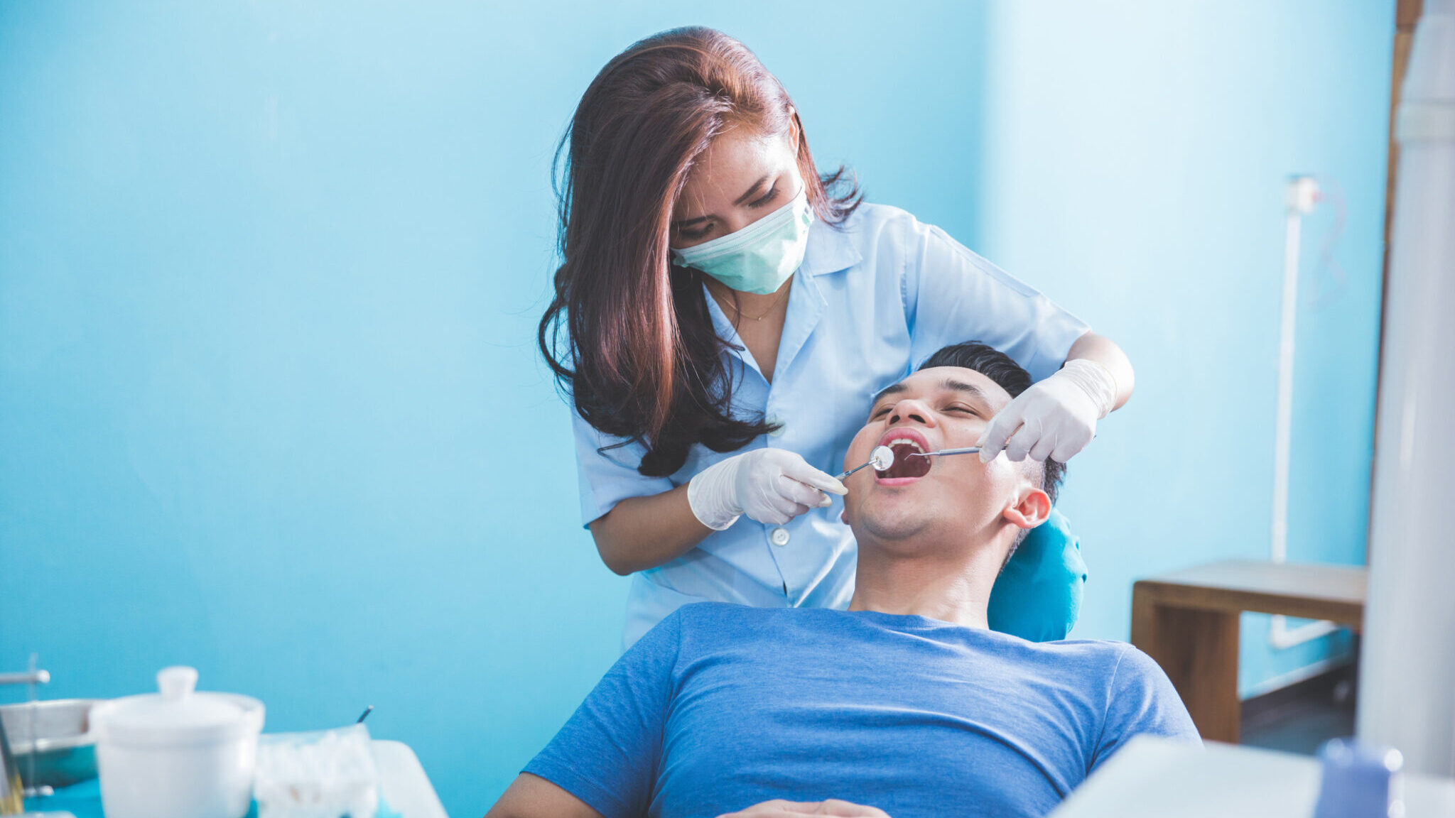 dentists examining and working on young male patient alternate text for this image