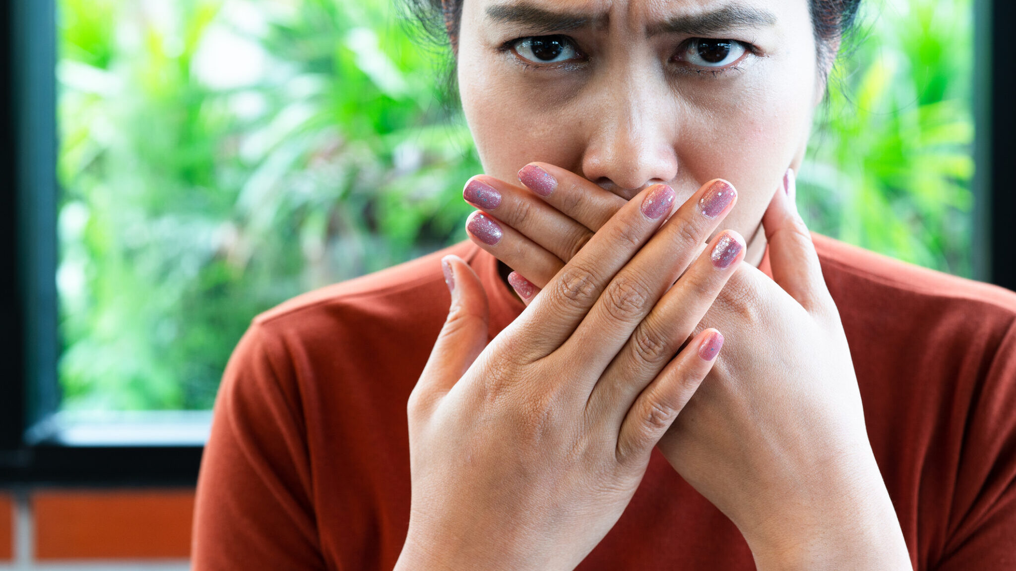 Woman with bad breath covering mouth, halitosis concept alternate text for this image