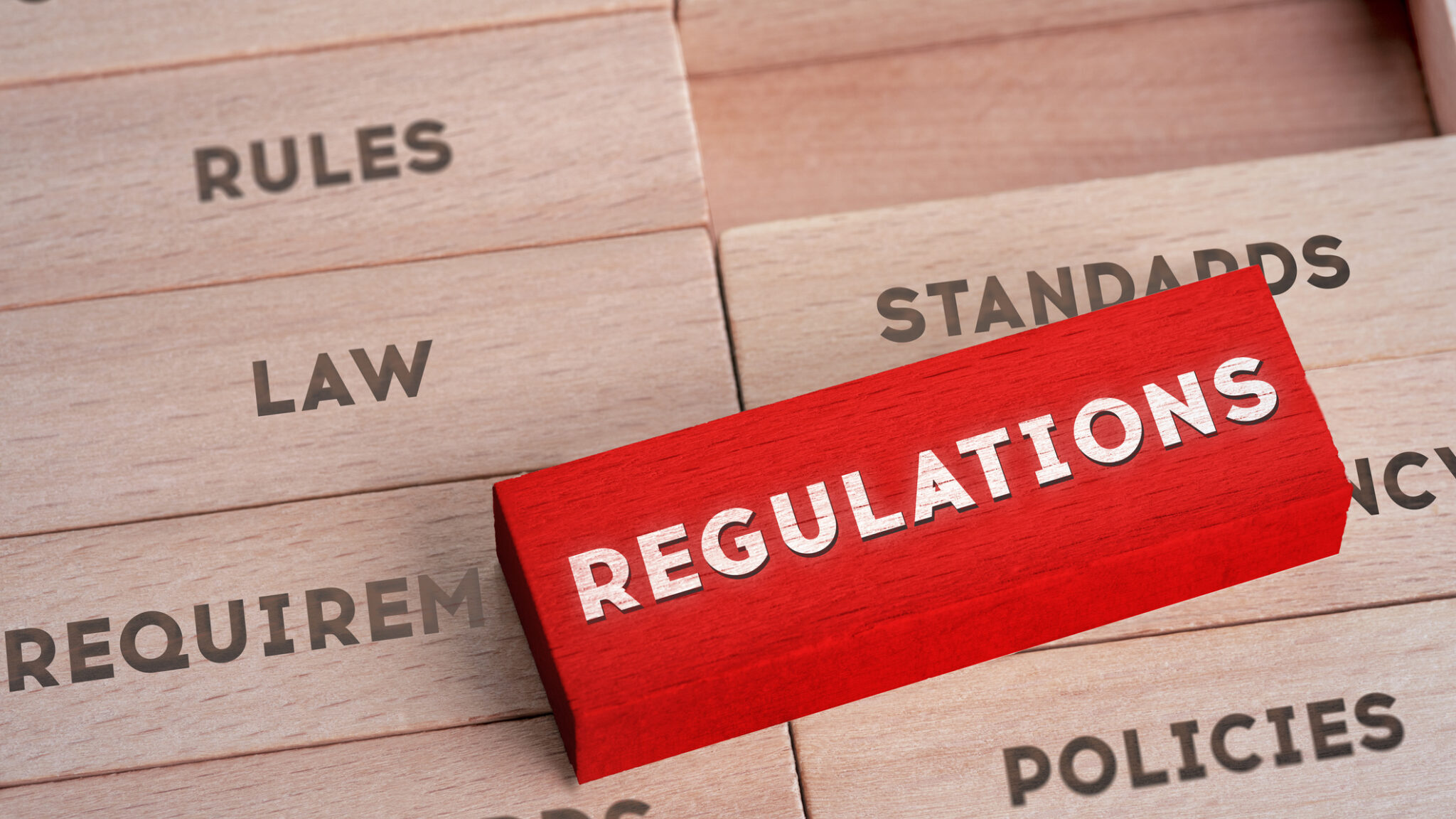 Regulations Concept with Wooden Blocks in Red Color alternate text for this image