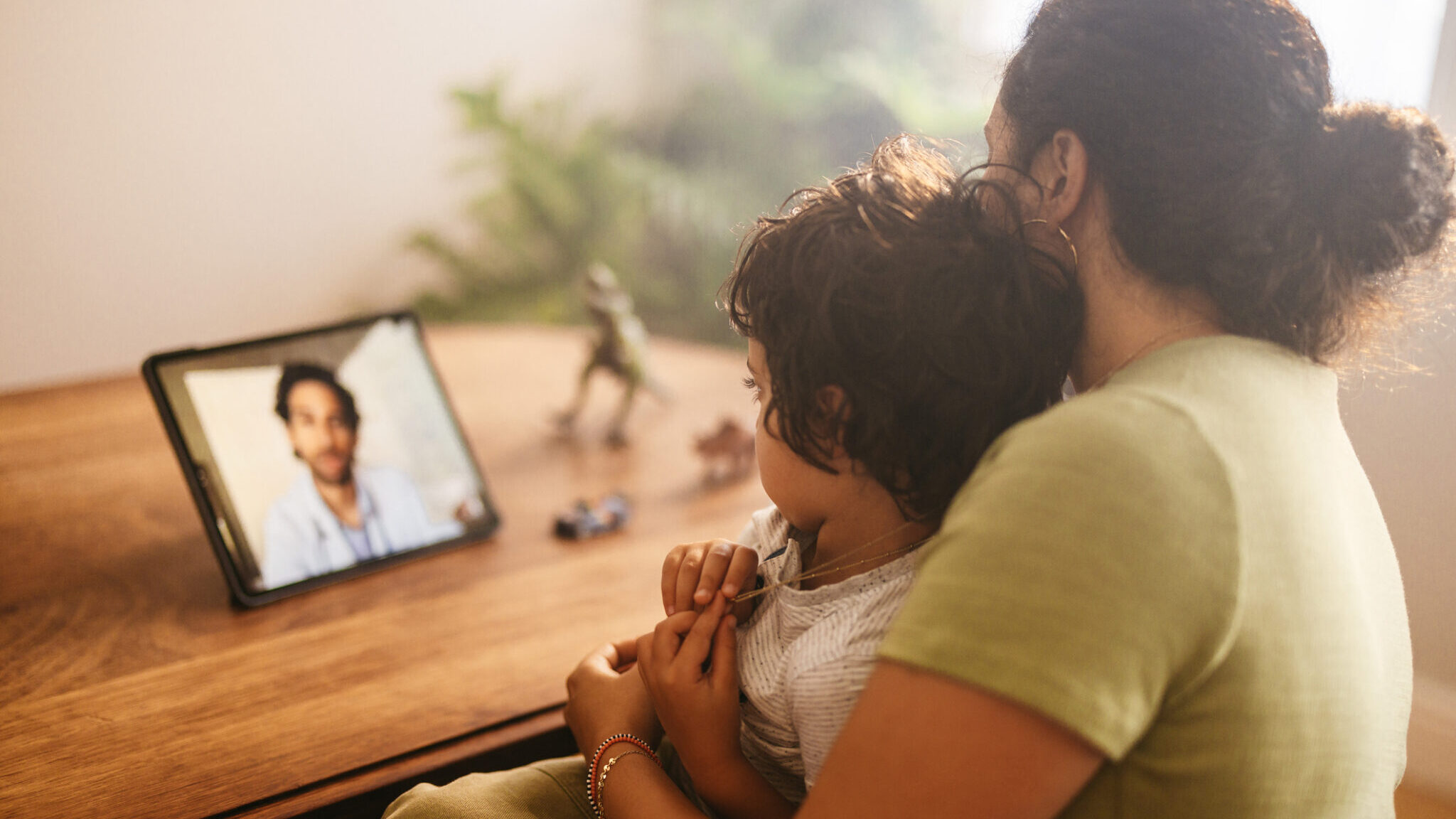 Mother and child video calling their family doctor at home alternate text for this image