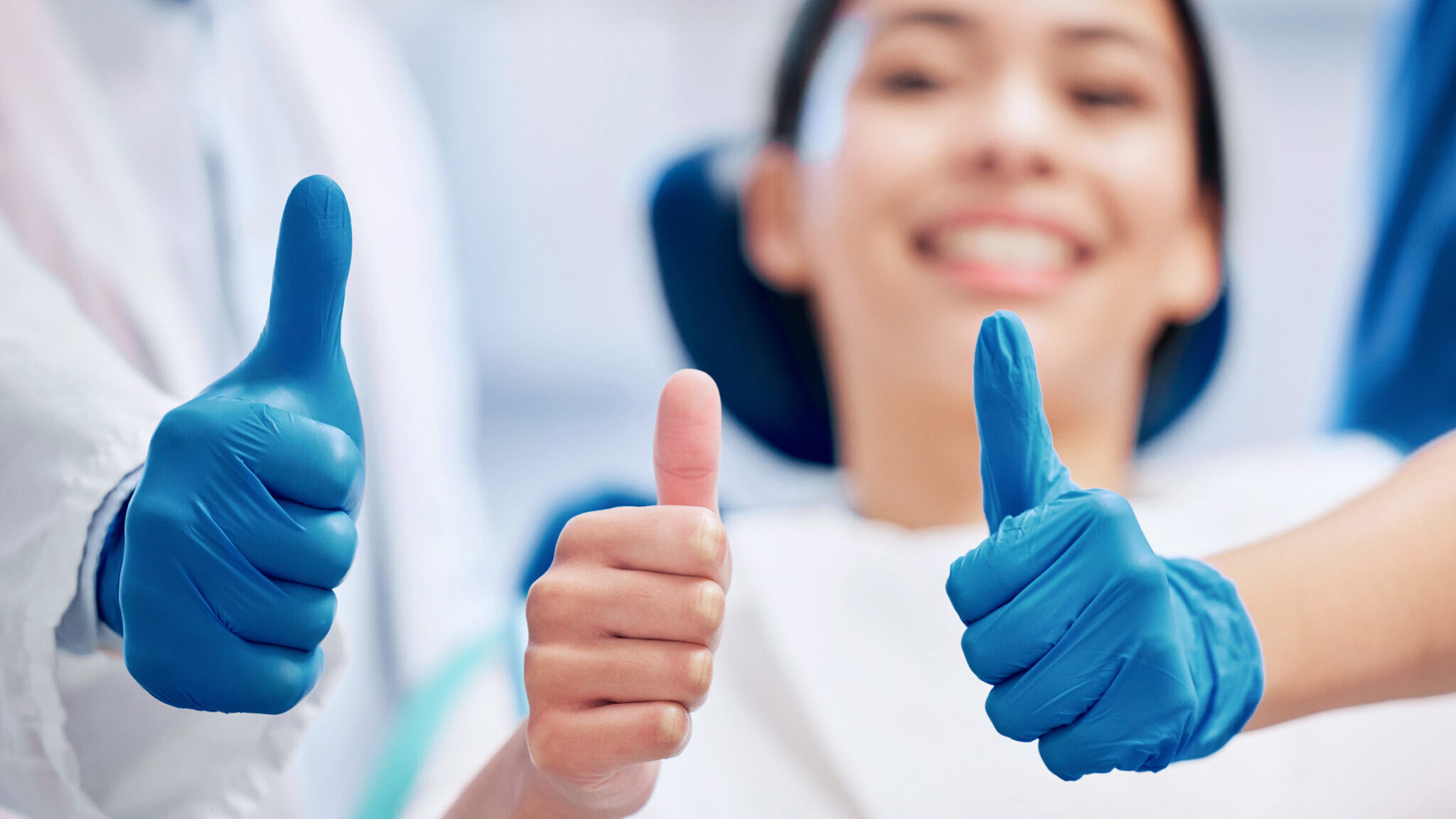 Shot of a young woman giving the thumbs up with her dentist alternate text for this image