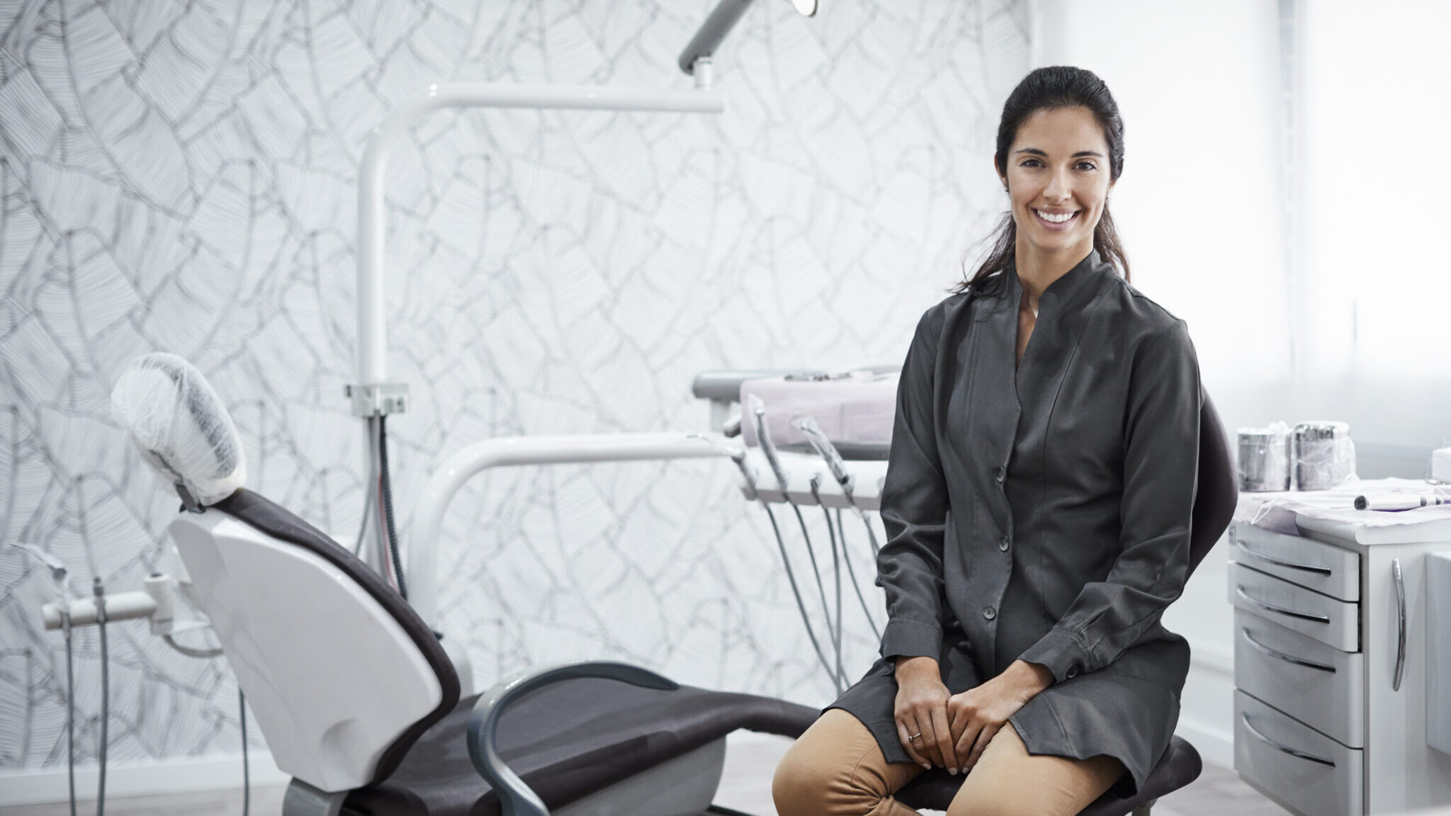 Confident female dentist sitting in clinic alternate text for this image