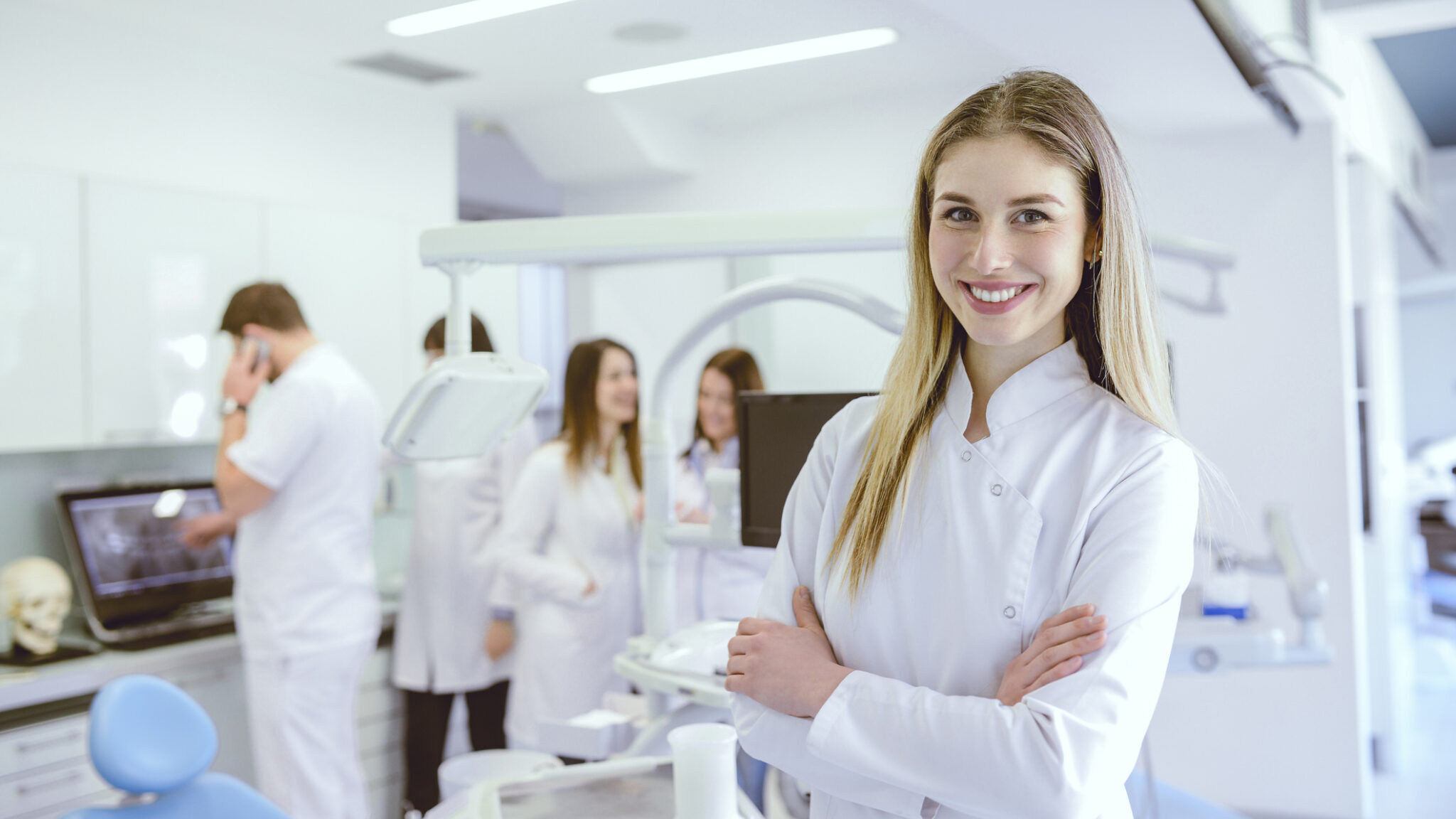 Young Beautiful Dentist Posing in Crowded Clinic alternate text for this image