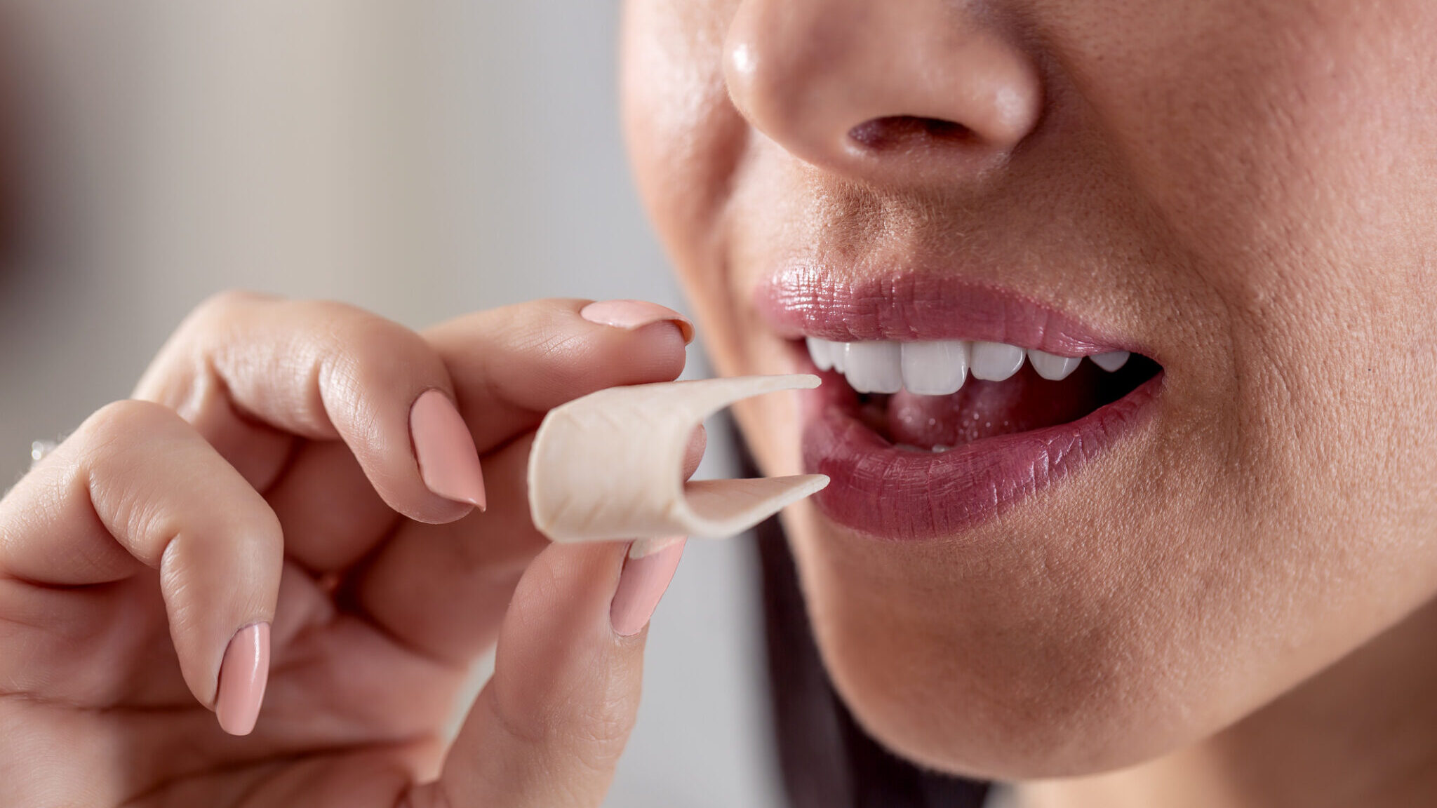 Detail of a woman putting a folded chewing gum into her mouth. alternate text for this image
