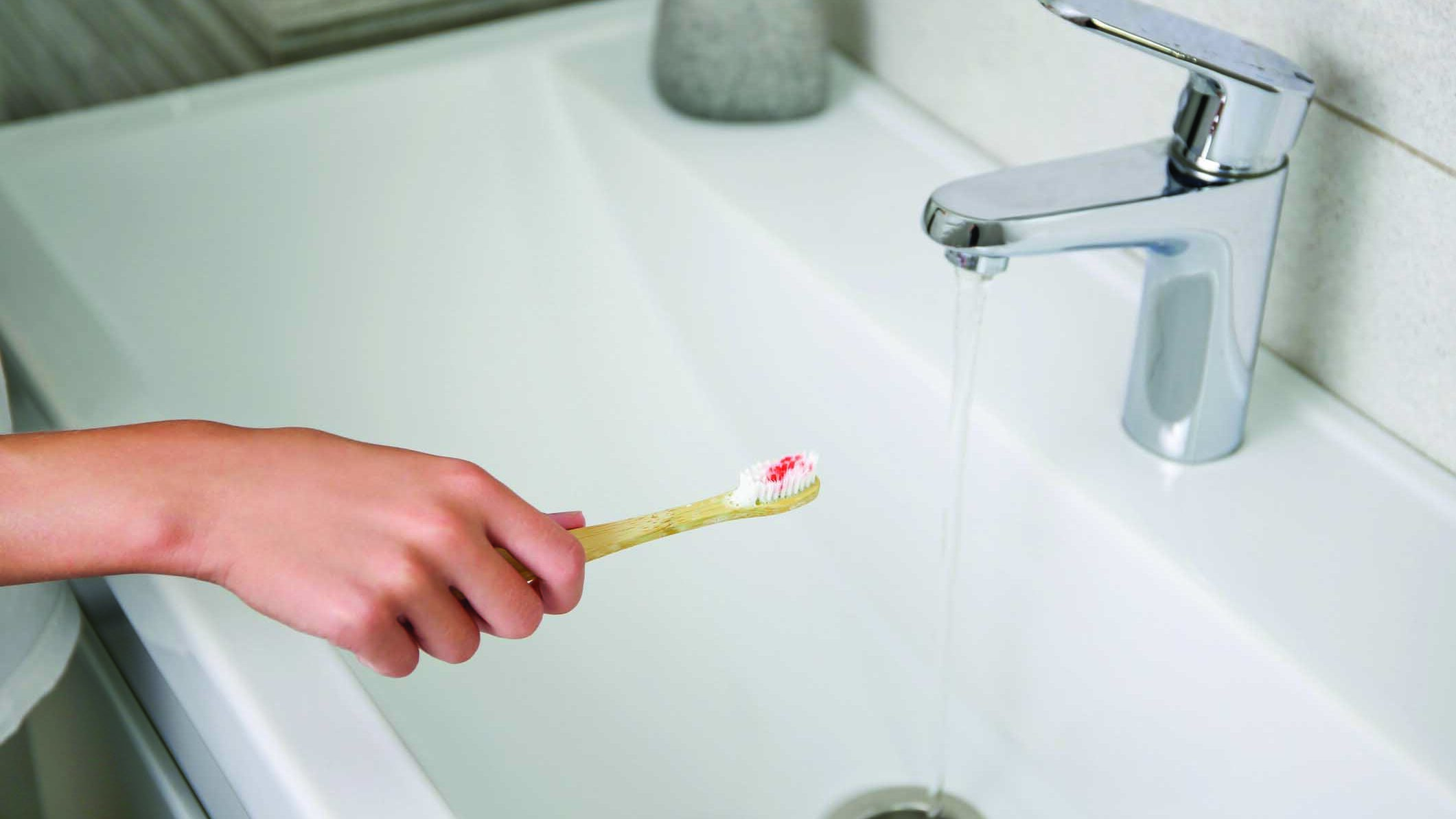 Blood on toothbrush on background of sink. Selective focus on the toothbrush. alternate text for this image