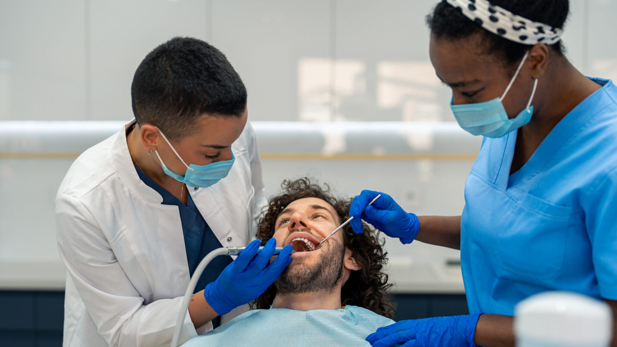 Female dentist is drilling man’s tooth alternate text for this image