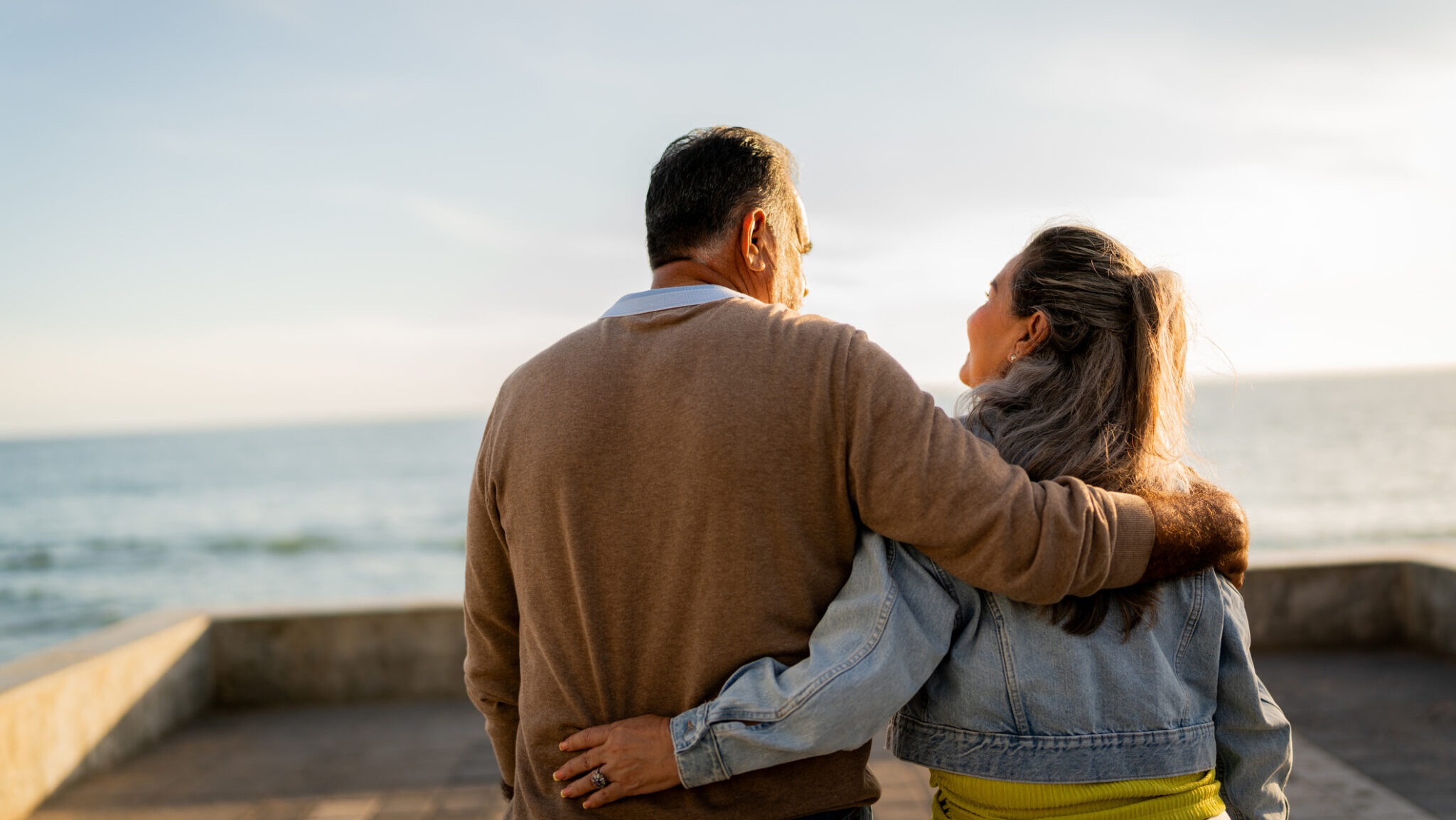 Senior couple walking and talking on coastline pier