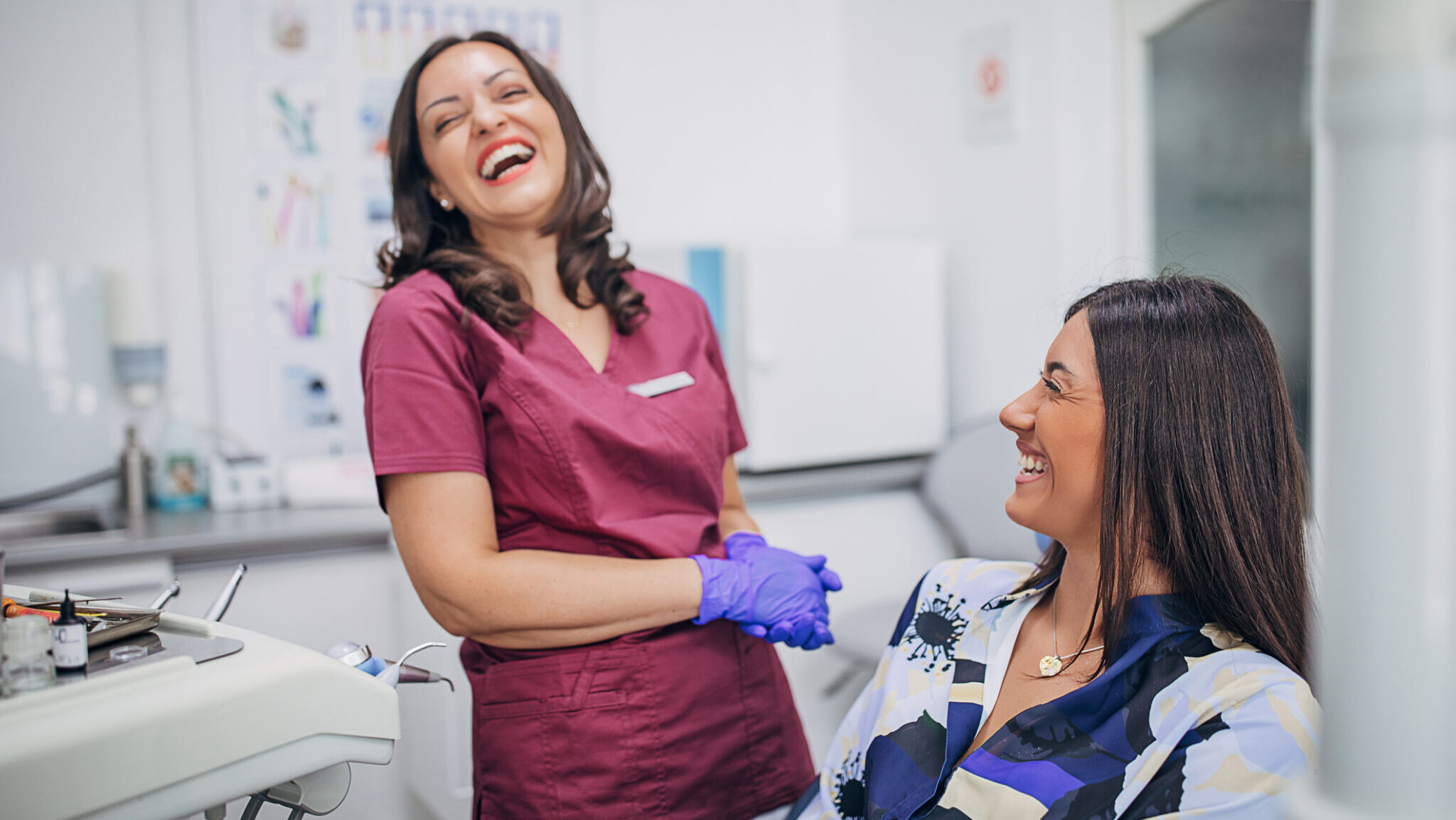 Two women, beautiful young woman and female dentist doctor laughing together at the dentist ordination.