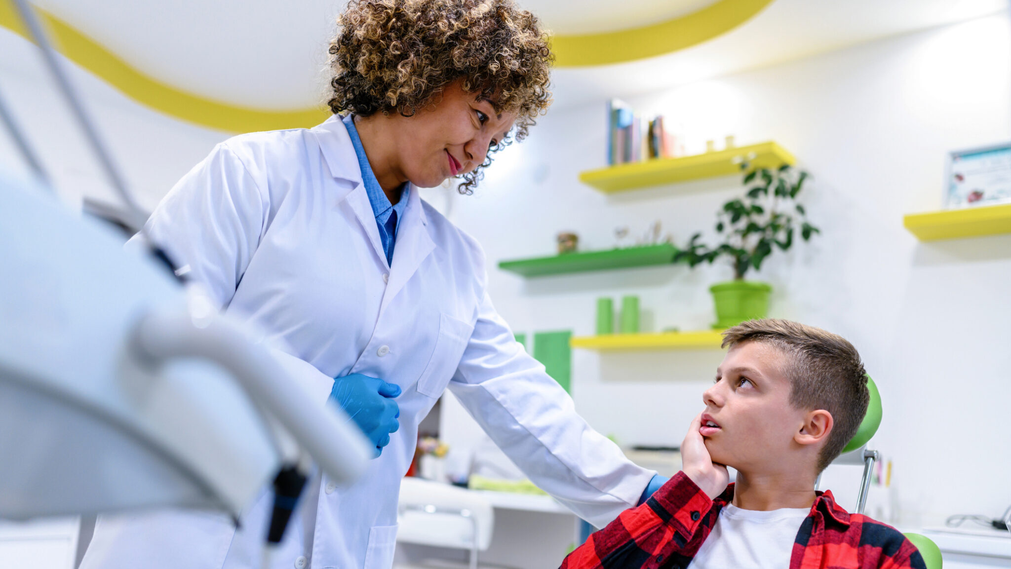 Boy complaining about toothache to his dentist during a dental check-up.