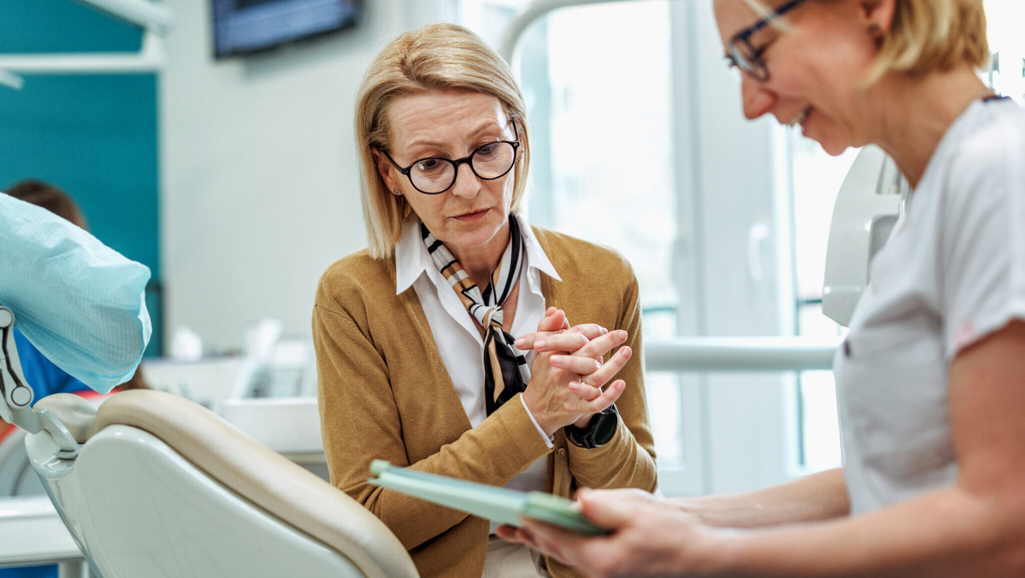 Senior woman talking with female dentist at the doctor's office