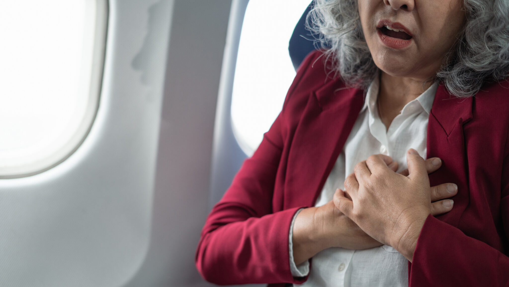 Mature with chest pain with nausea feeling sick while sitting in the airplane , Passengers near the window.