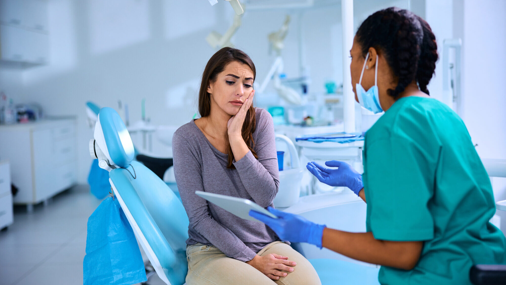 Young woman with toothache having appointment at dentist's office.