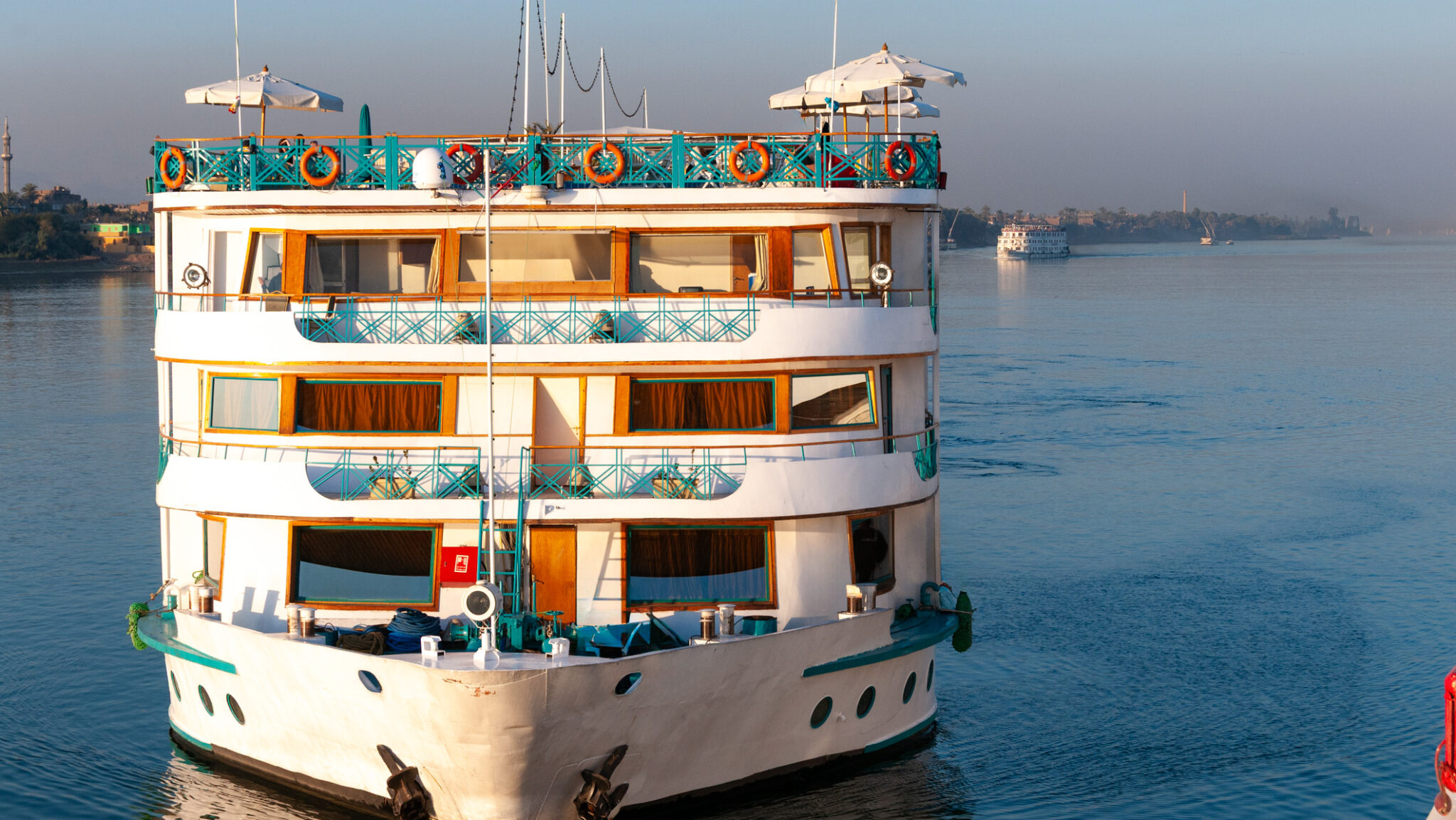 A multi-deck river cruise boat sails on the calm waters of the Nile River. (iStock)