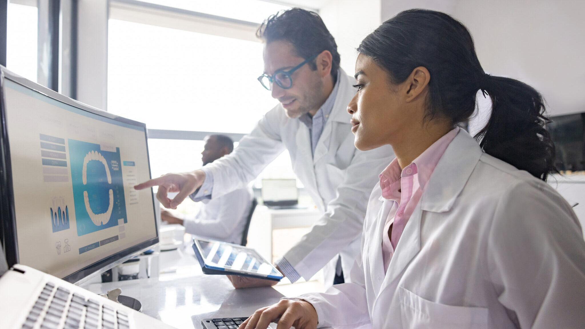 Team of Latin American engineers working at 3D printing lab and designing a dental mold using a computer